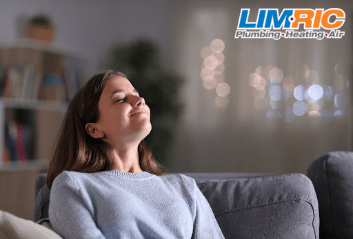 Woman sitting on couch enjoying fresh air from new IAQ products in her home.