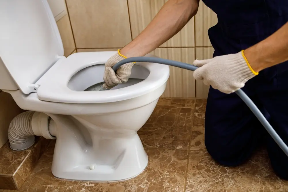 plumber unclogging blocked toilet with hydro jetting service